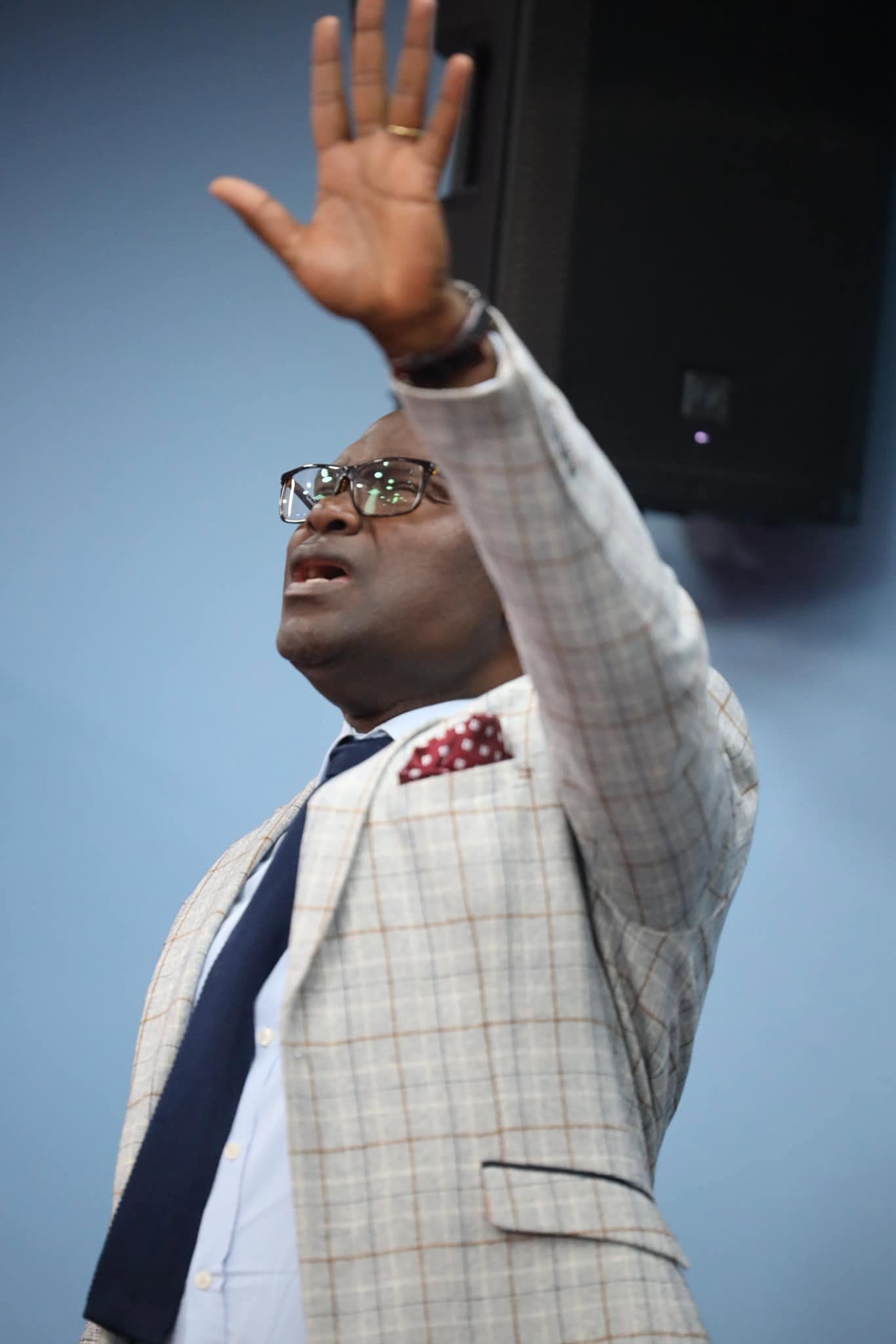 The pastor with a hand lifted in worship